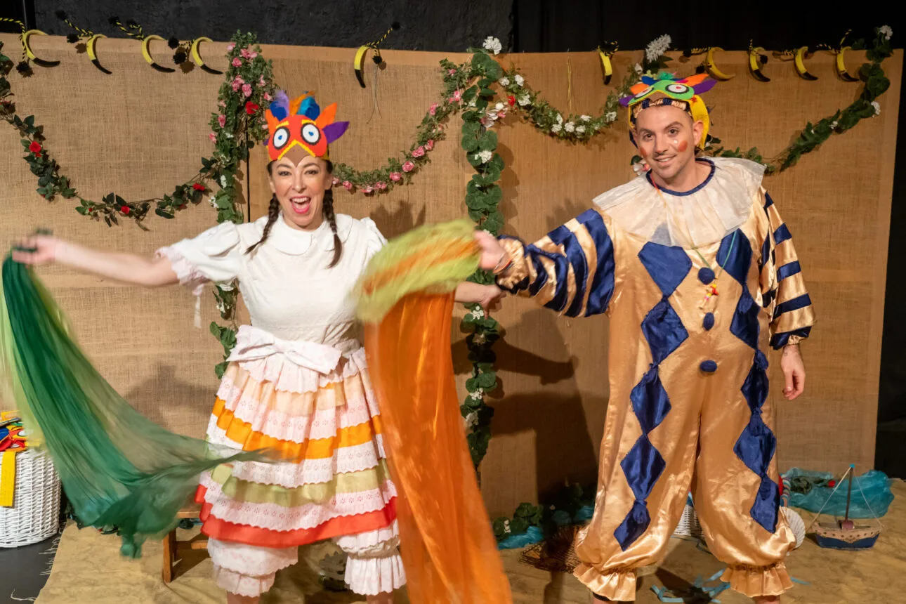 Δυο ηθοποιοί με τα κοστούμια των ρόλων μπροστά στο σκηνικό της παράστασης θεάτρου για παιδιά